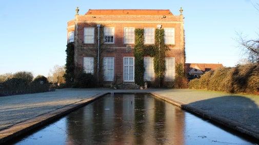 Frozen lily pond with Hinton Ampner house in the background
